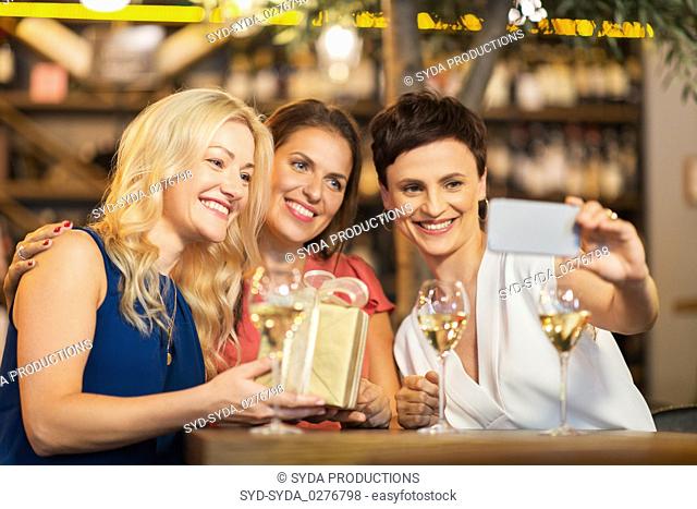 women with gift taking selfie at wine bar