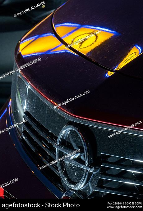 04 August 2023, Saxony-Anhalt, Wittenberg: The logo of car manufacturer Opel is reflected in the hood of a car on the premises of an Opel dealership in...