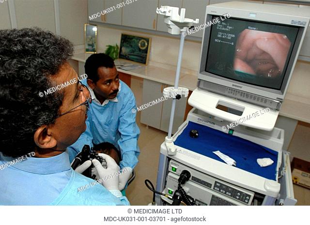 A doctor performs an endoscopic procedure./nImage shows doctor looking at the monitor the view from the endoscopic probe and a nurse tending to the patient