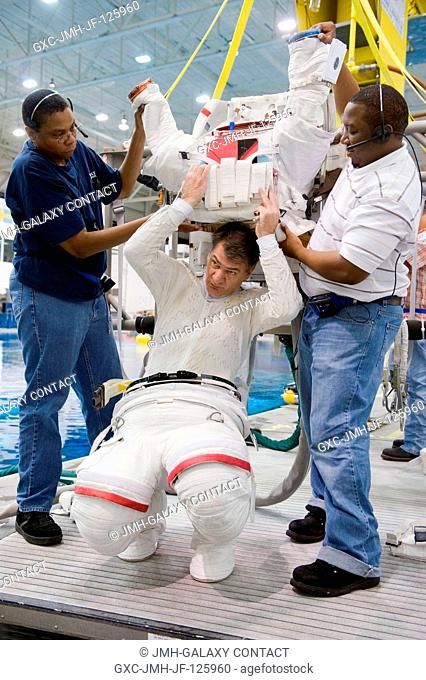 European Space Agency (ESA) astronaut Paolo Nespoli, Expedition 2627 flight engineer, gets help donning a training version of his Extravehicular Mobility Unit...