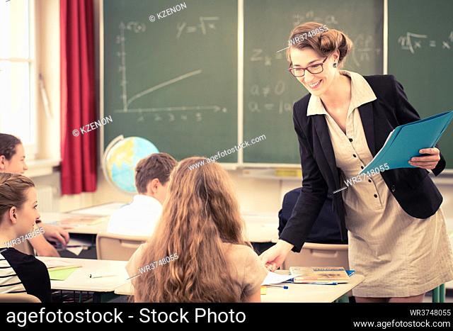 Teacher handing out class work to her students