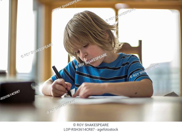 England, London, Hackney. Seven year old boy drawing at the table