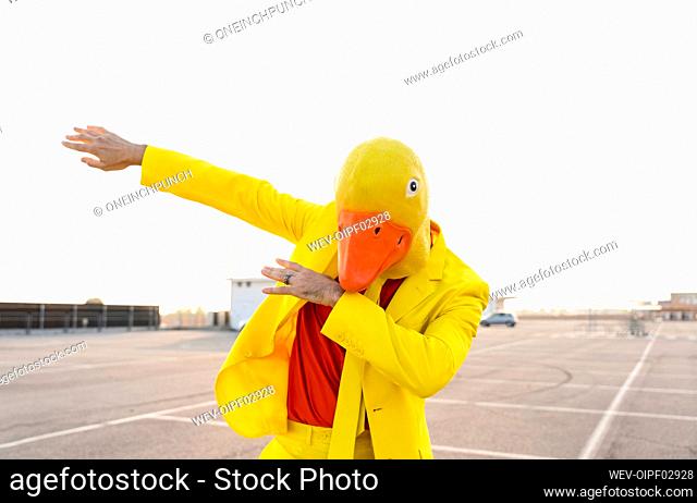 Man wearing yellow duck mask dancing in parking lot