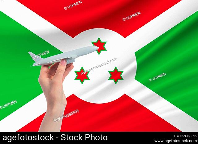 Airplane in hand with national flag of Burundi. Travel to Burundi