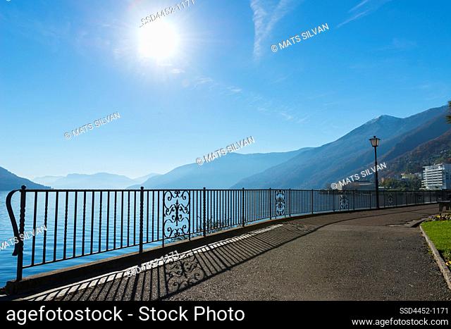 Walkway on the Waterfront with Alpine Lake Maggiore with Mountain and Sunlight in Brissago, Switzerland