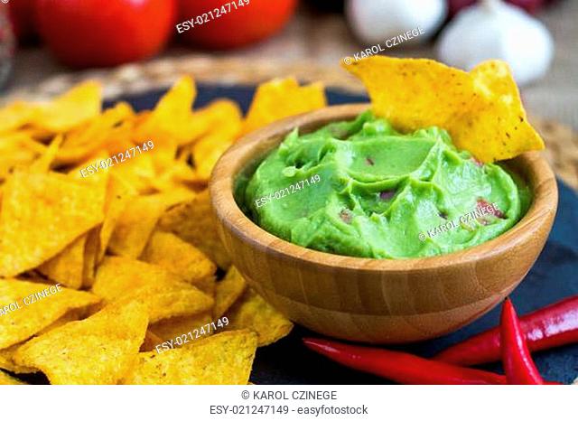 Guacamole in Wooden Bowl with Tortilla Chips and Ingredients