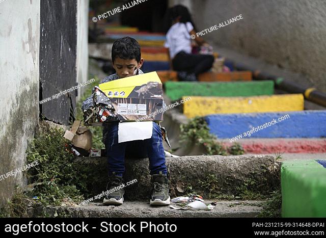 15 December 2023, Venezuela, Caracas: A child from the poor neighborhood of Petare opens a gift during the gift handover of the ""A toy
