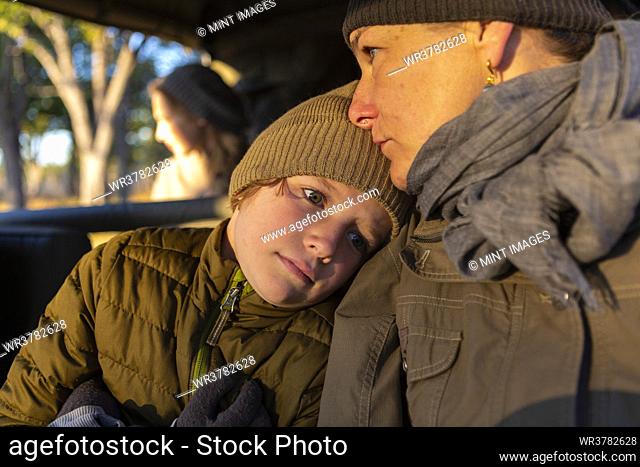 Close up of a boy and his mother in a safari jeep in early morning sun