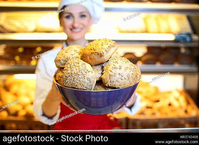 Fresh bread rolls presented by an attractive young sales woman in bakery