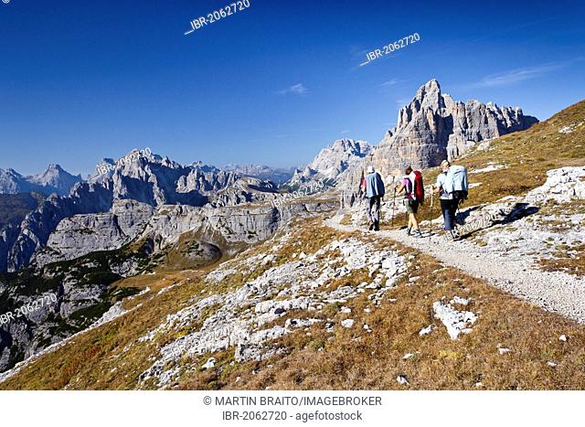 Hikers at the Pian di Cengia ridge, climbing Mt Paterno, Tre Cime di Lavaredo massif, the Cadini di Misurina mountain group and Mt Monte Cristallo in the back
