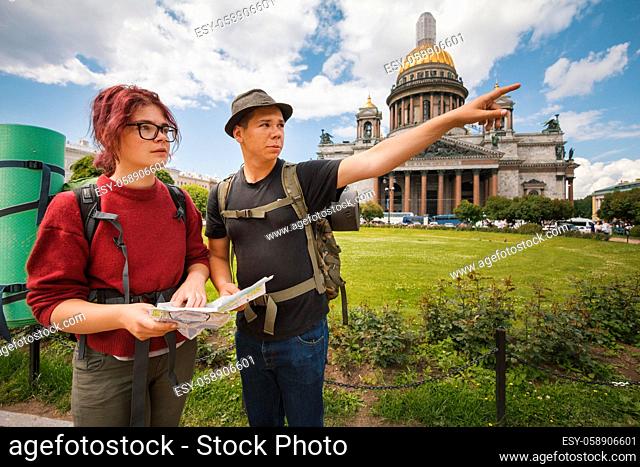 Young tourists check the route on the paper map in landmark of Saint Petersburg, Russia - close up