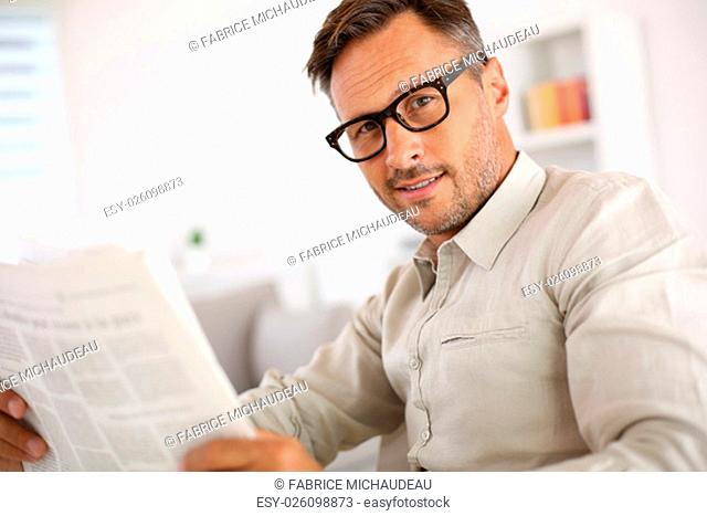 Friendly guy with eyeglasses reading newspaper