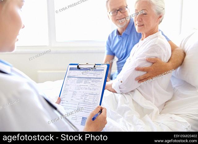 old couple and doctor with clipboard at hospital