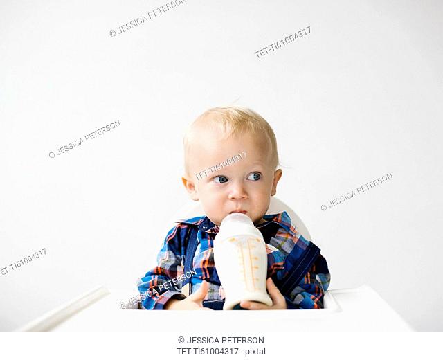 Studio shot of boy (12-17 months) drinking from baby bottle