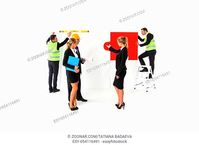 Team of business people and workers assmebling puzzle isolated on white