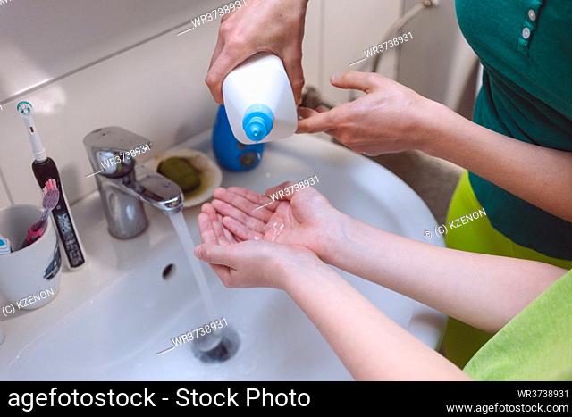 Mother disinfecting her hands of her son due to covid-19