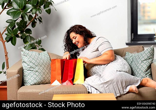 happy young woman with shopping bags at home