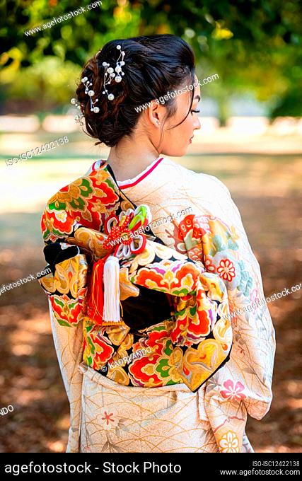 Rear view of woman wearing kimono standing in park