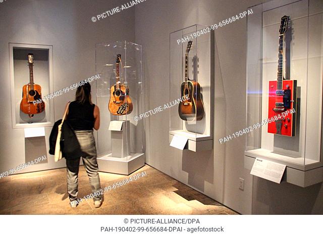 01 April 2019, US, New York: A visitor takes a photo in the exhibition, on the right hangs a red electric guitar Gretsch Twang Machine