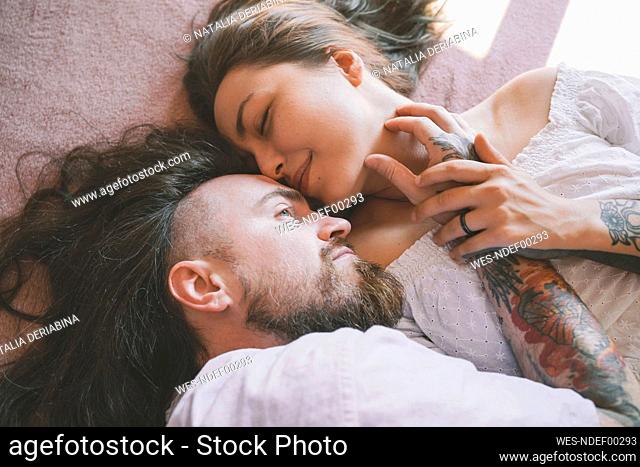 Romantic hipster couple lying on bed at home