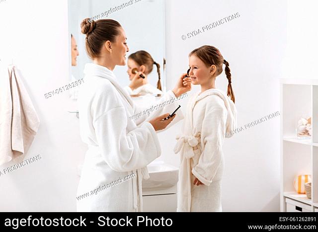 mother and daughter applying make up in bathroom