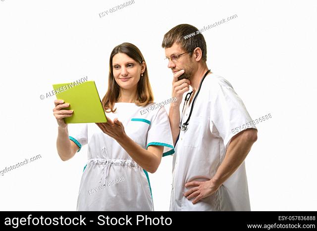 The nurse shows the test results in a tablet computer, the doctor looks thoughtfully at the screen