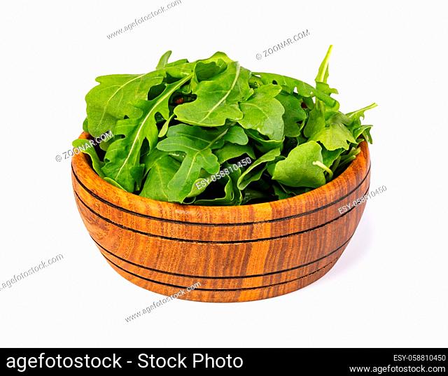 Fresh green arugula leaves on wooden bowl isolated on white background