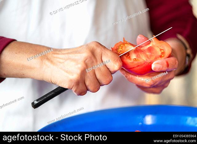 Woman cutting a tomato with a knife. Preparation of products for cooking