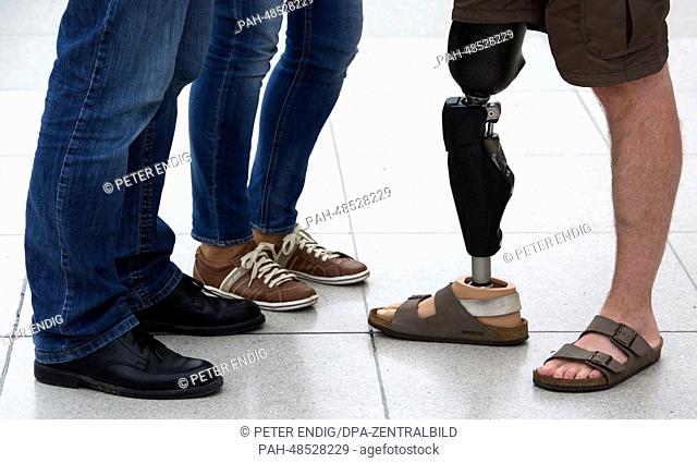 A man with a leg prosthesis (R) by company Otto Bock (Lower Saxony) stands next to two other people at the trade show OT World 2014 in Leipzig, Germany