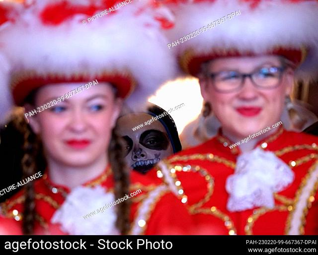 20 February 2023, Schleswig-Holstein, Marne: A boy in disguise stands behind two women of the Marner Karnevals Gesellschaft (MKG) guard at the town hall on Rose...