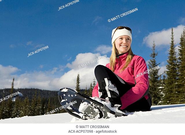Young woman rests after snowshoeing, Sun Peaks Resort, British Columbia, Canada