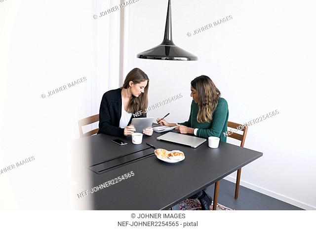 Two women using laptop in office