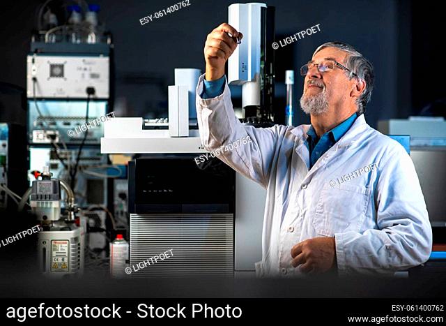 Senior scientist in a chemistry lab carrying out research - looking at gas chromatography samples, preparing the analysis on a modern gas chromatographer (color...