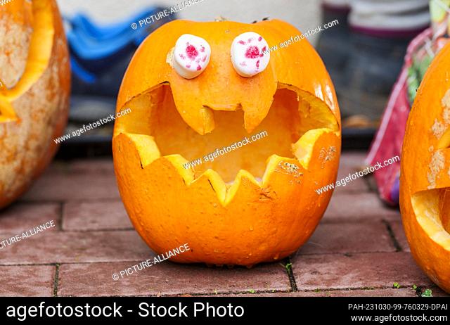 30 October 2023, Hesse, Wiesbaden: A spooky carved pumpkin stands in a front yard for decorative purposes. In the ""Housing Areas"" Aukamm and Crestview
