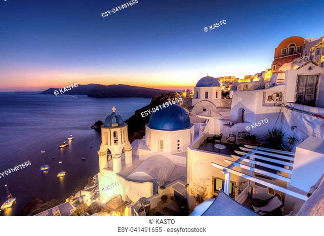 Cityscape of Oia, traditional greek village with blue domes of churches, Santorini island, Greece at dusk