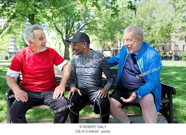 Active senior men friends talking on park bench