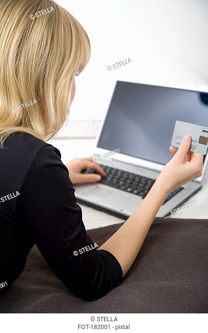 Young woman using a credit card online with her laptop