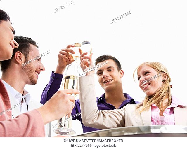 A group of young people chinking glasses, celebrating