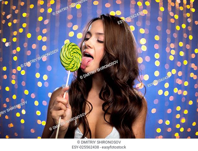 Pretty girl with long hair licking lollipop