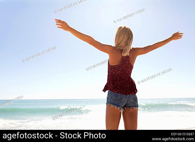 Young caucasian woman raising arms on the beach