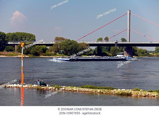 Frachtschiff auf dem Rhein mit zwei Anglern und der Rheinbruecke, Leverkusen, Bergisches Land, Nordrhein-Westfalen, Deutschland, Europa