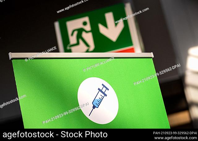 23 September 2021, Lower Saxony, Hanover: A ""syringe"" pictogram can be seen under an ""emergency exit"" pictogram at the vaccination centre on the exhibition...