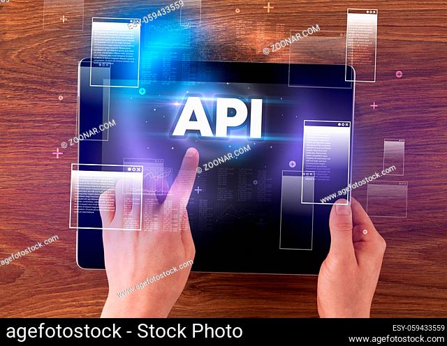Close-up of a hand holding tablet with API abbreviation, modern technology concept