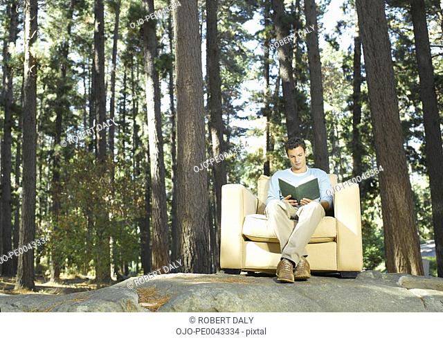 A man reading outdoors in the woods