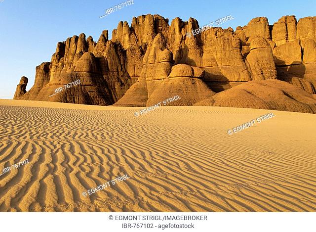 Eroded rock formations rising out of desert sand dunes, ripples in Tin Akachaker, Tassili du Hoggar, Wilaya Tamanrasset, Sahara Desert, Algeria, North Africa