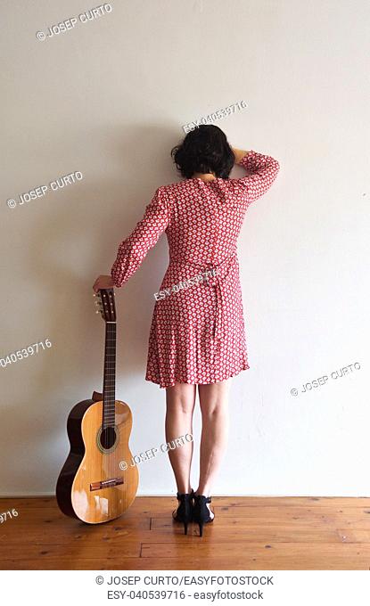 woman from behind with guitar on a wall