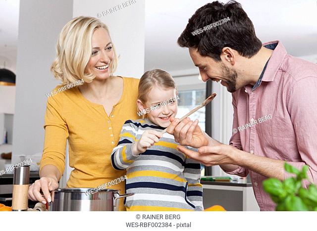 Mother, father and daughter cooking in kitchen