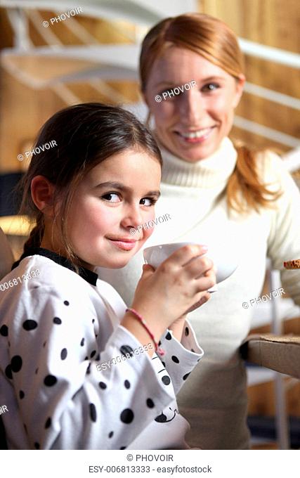 Little girl drinking from large mug at breakfast