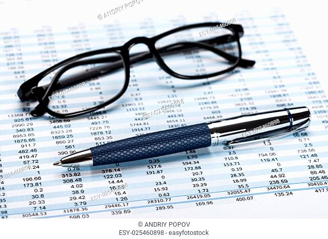 Close-up Of A Financial Data Sheet With Eyeglasses And Ballpen