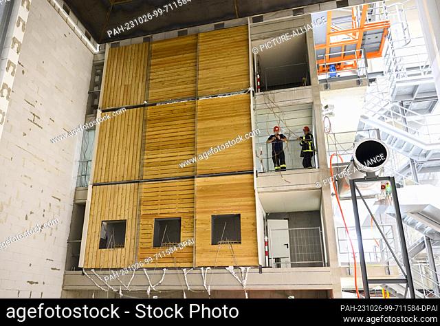 PRODUCTION - 10 October 2023, Lower Saxony, Brunswick: Firefighters stand next to a three-story wooden façade during a research project at the Center for Fire...